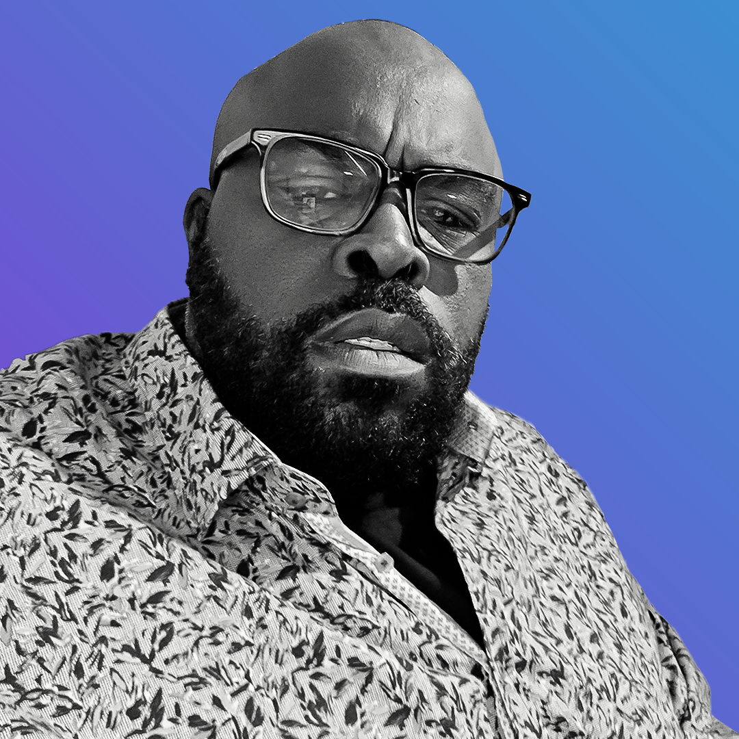 A person with a beard and glasses, wearing a patterned shirt, is looking directly at the camera against a gradient blue and purple background. OCIDM,io Branding and Digital marketing Hamilton, Toronto, Oakville, Mississauga