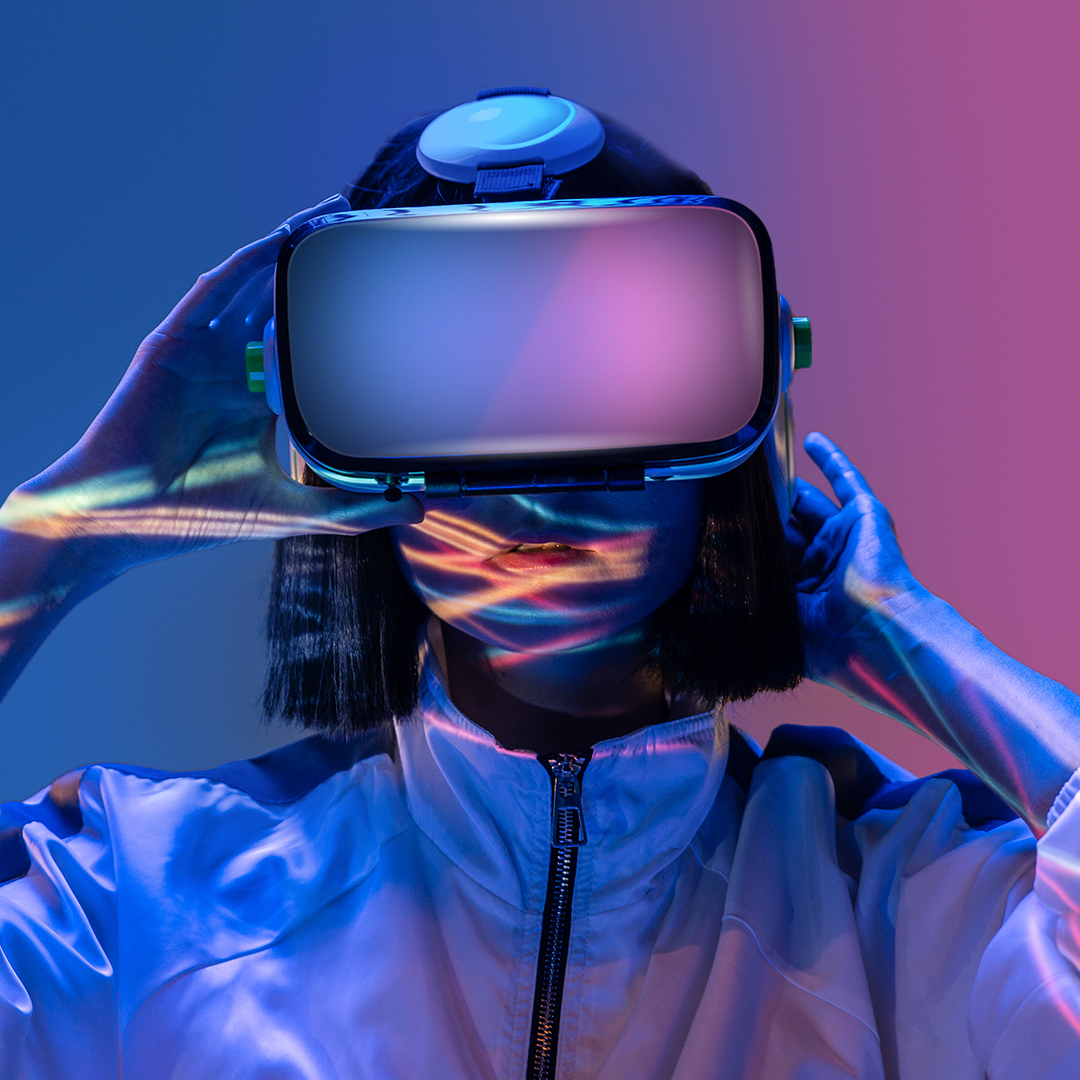 Person wearing a virtual reality headset, illuminated by colorful lights, against a gradient purple and blue background. OCIDM,io Branding and Digital marketing Hamilton, Toronto, Oakville, Mississauga