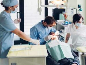 Dentist and assistants performing a dental procedure on a patient in a clinic setting, showcasing effective strategies for delivering excellent care. OCIDM,io Branding and Digital marketing Hamilton, Toronto, Oakville, Mississauga